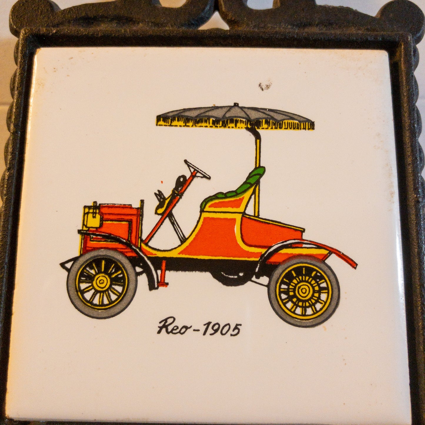 Cast Iron and Tile, 1905 Reo Automobile Trivet,Made in Japan, 3 by 3 inch tile, 6.5  tall by 3.5 wide Inches